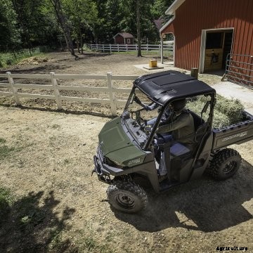 Green Polaris Ranger in a farm yard with a red barn