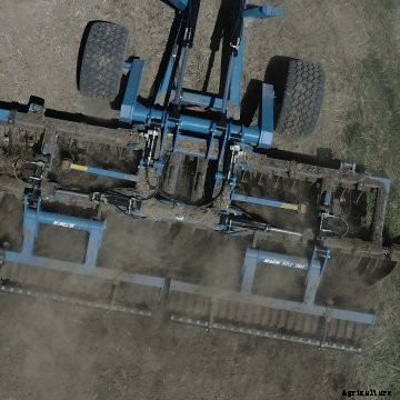 Drone photo of a blue Kinze Mach Till running in a field