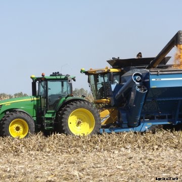 A New Holland combine unloads into a Kinze grain cart.