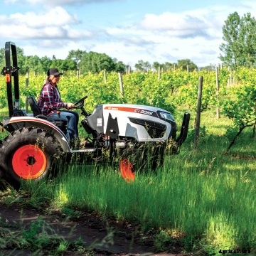Open station Bobcat compact tractor mowing in a field