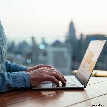 A man's hands working at a laptop computer sitting on a table