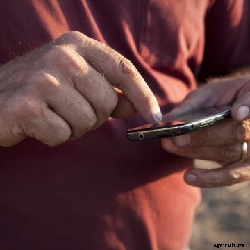 Farmer using a smartphone in a field.