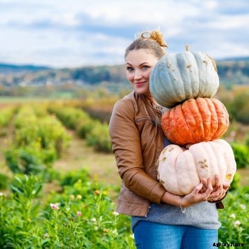 A woman holding pumpkins.