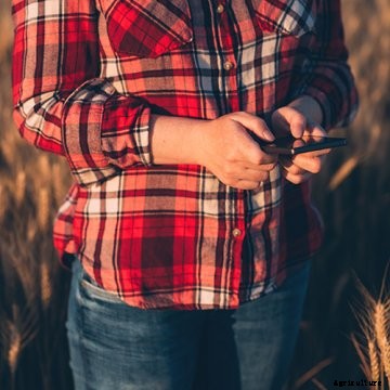 A farmer in a field on a smartphone.