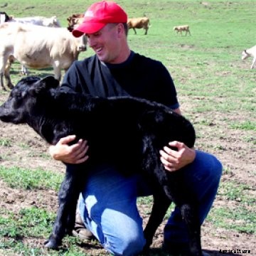 A young farmer holding a calf.