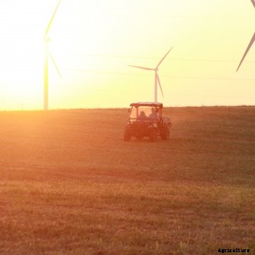 A UTV rides across a farm at sunset.